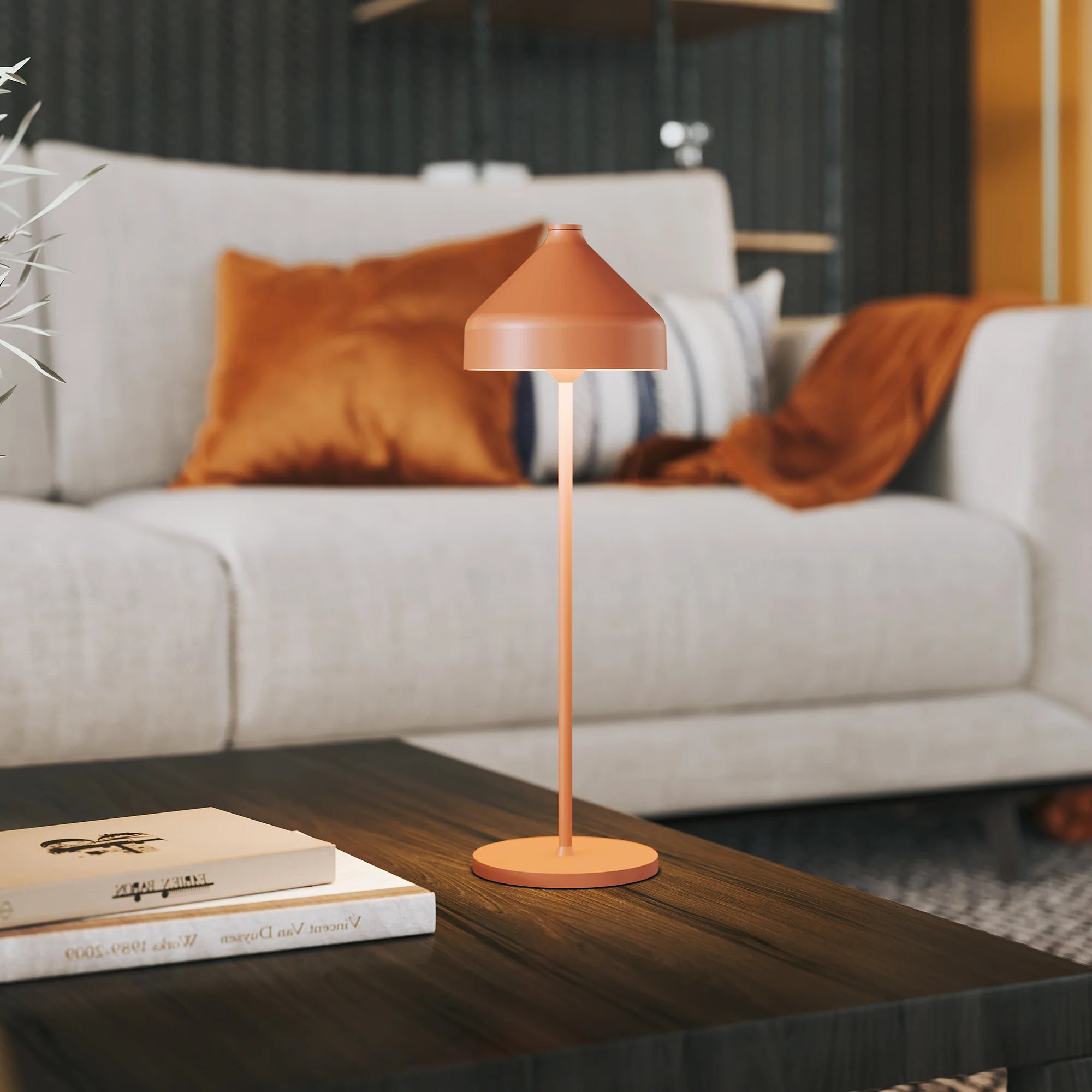 The terracotta Amelie Pro Cordless Lamp from Zafferano in a lounge on top of a table.