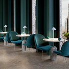 The white Amelie Pro Cordless Lamp from Zafferano in a business space, set on multiple tables.