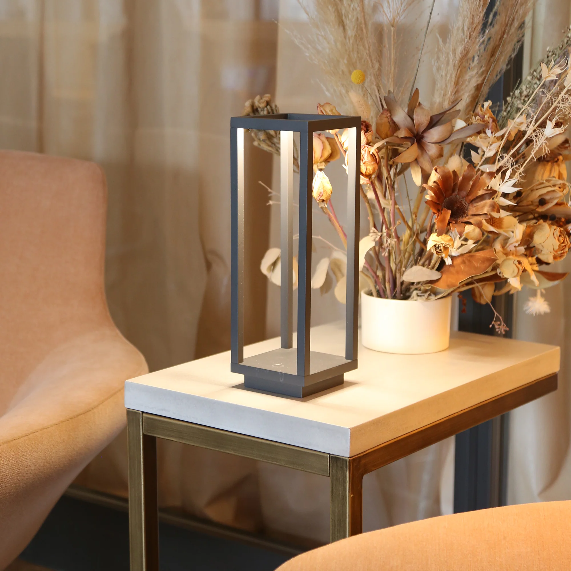 The dark gray Home Cordless Lamp from Zafferano in a business lounge between two chairs.