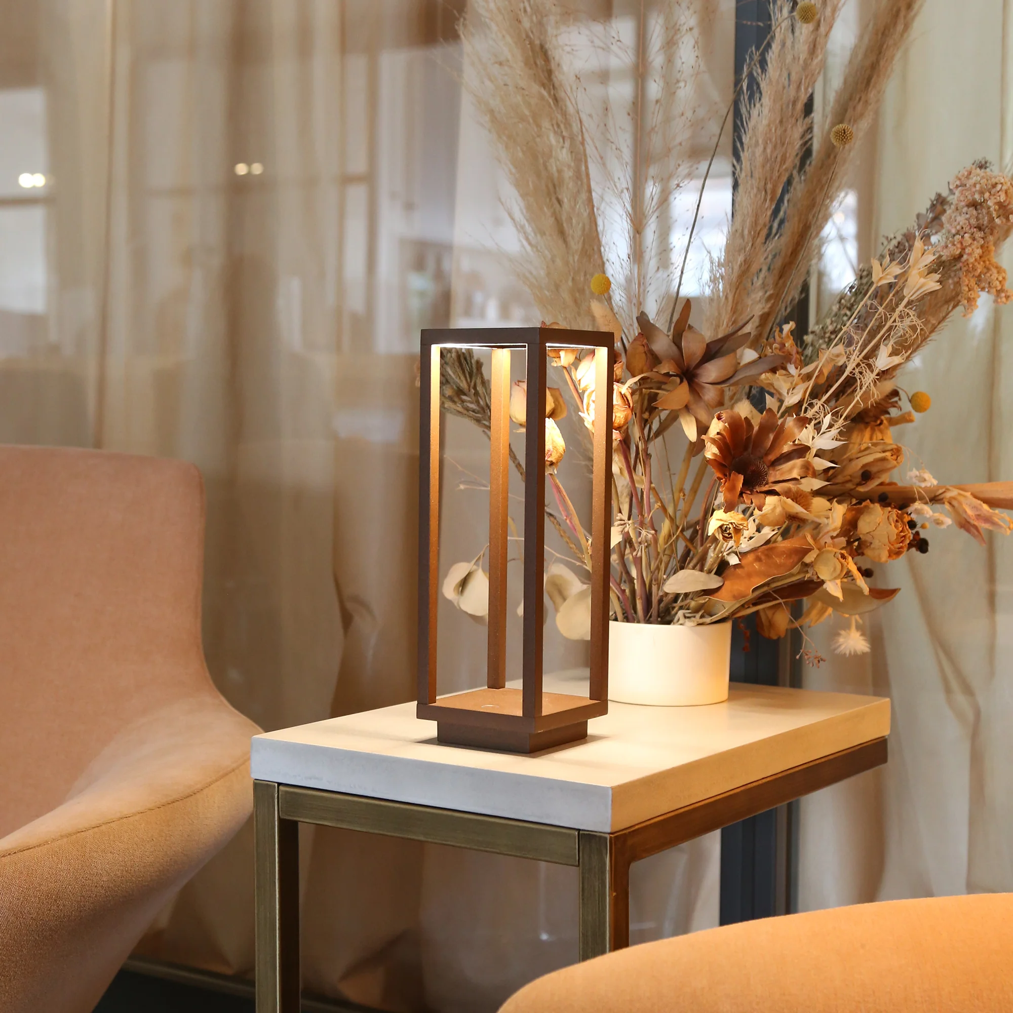 The rust Home Cordless Lamp from Zafferano in a lounge on top of an end table.