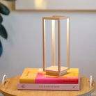 The sand Home Cordless Lamp from Zafferano on top of books in an office.