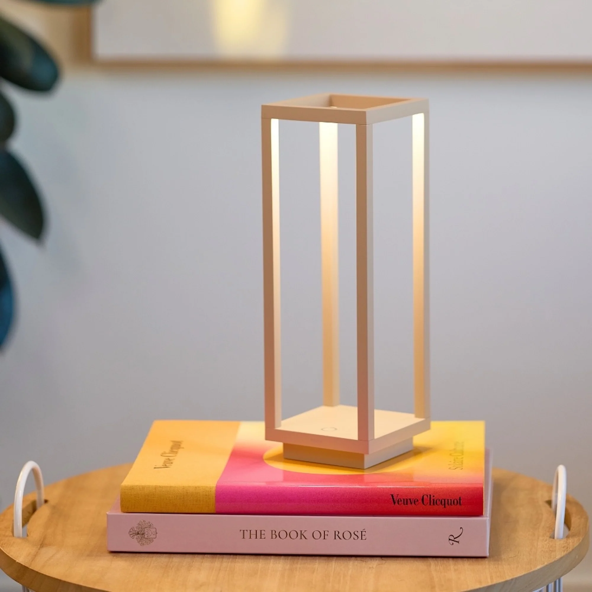 The sand Home Cordless Lamp from Zafferano on top of books in an office.