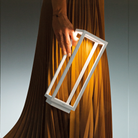 The white Home Cordless Lamp from Zafferano being handheld by a woman in a studio.