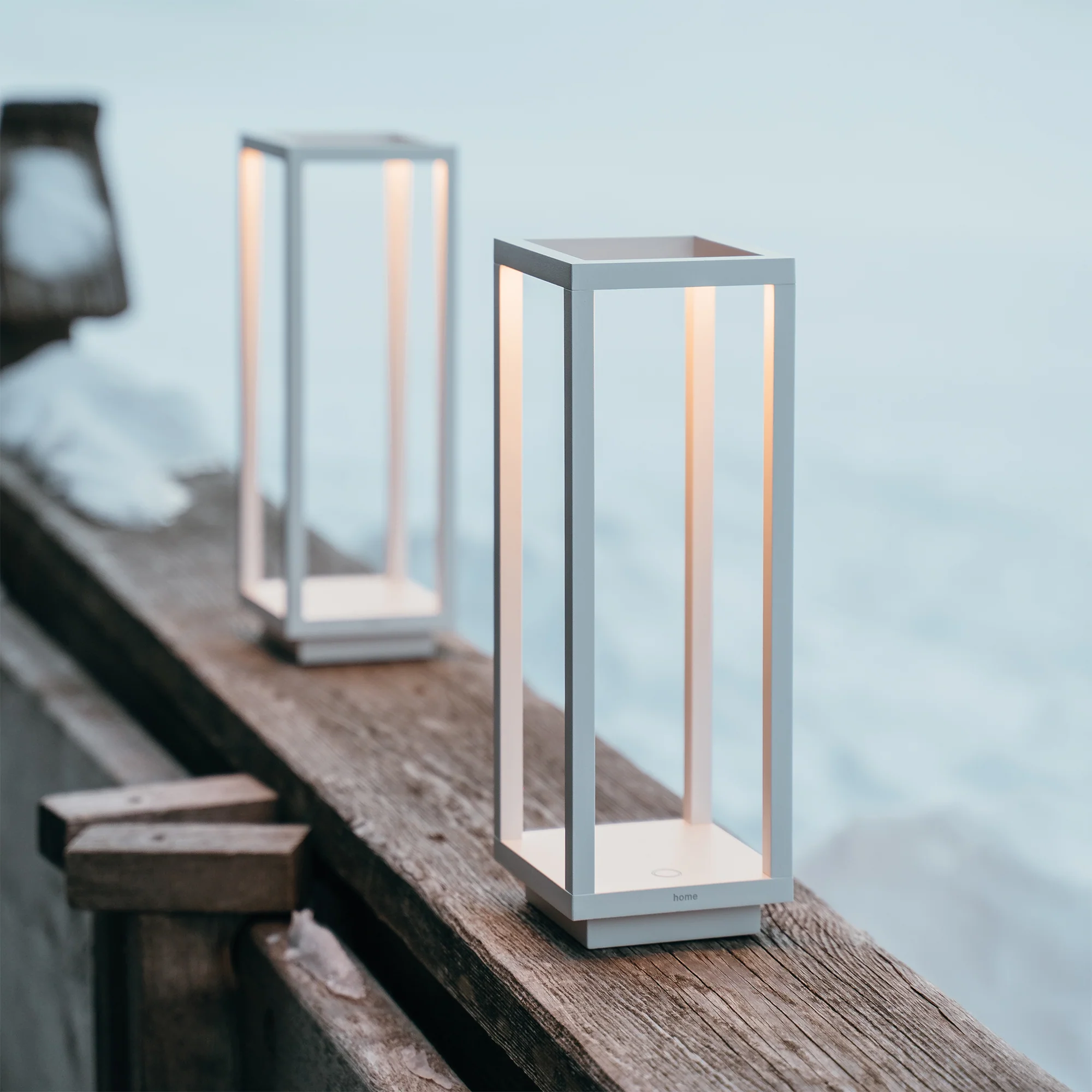 The white Home Cordless Lamp from Zafferano on a patio on the handrail.