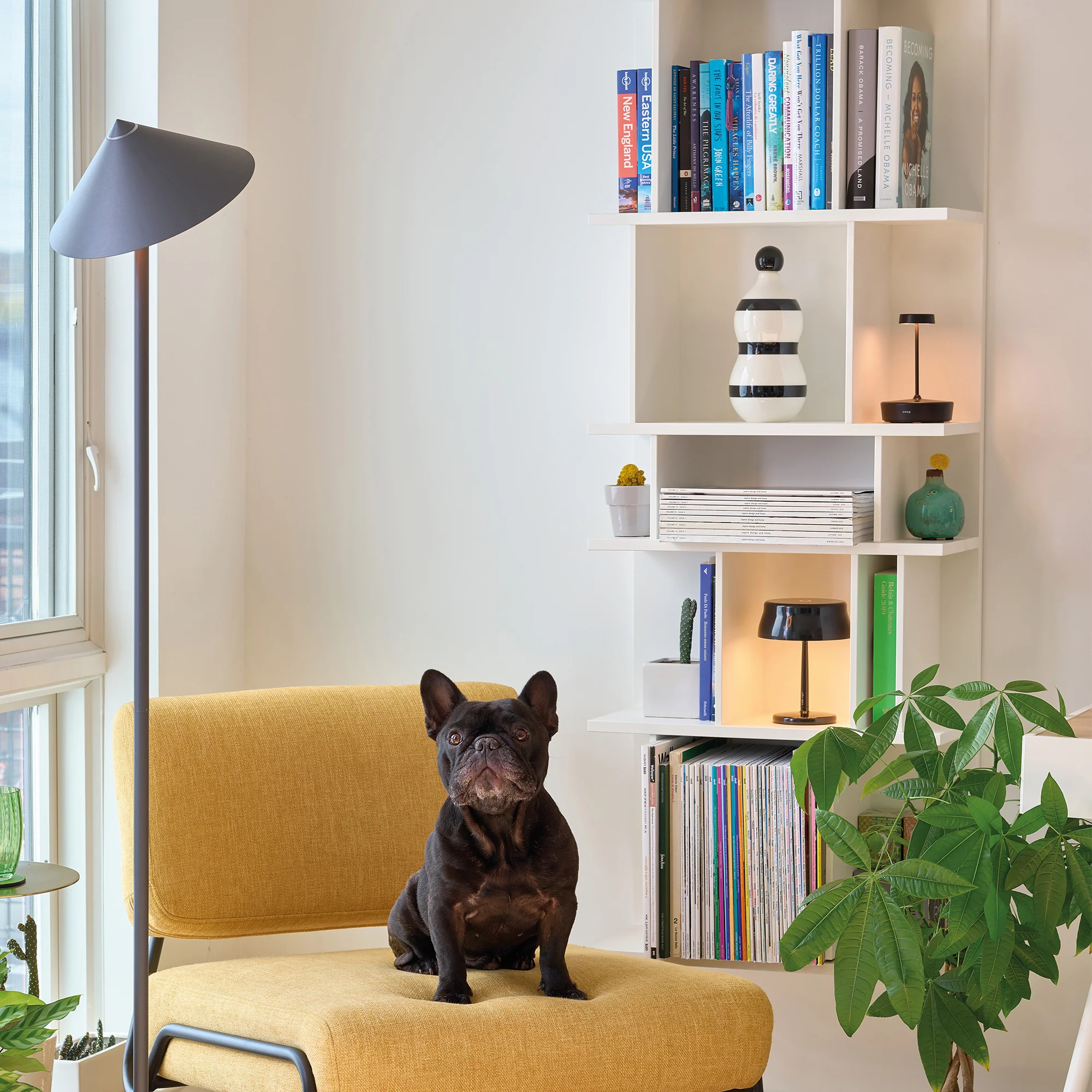 The titanium Pina XXL Cordless Floor Lamp from Zafferano in a lounge beside a lounge chair.