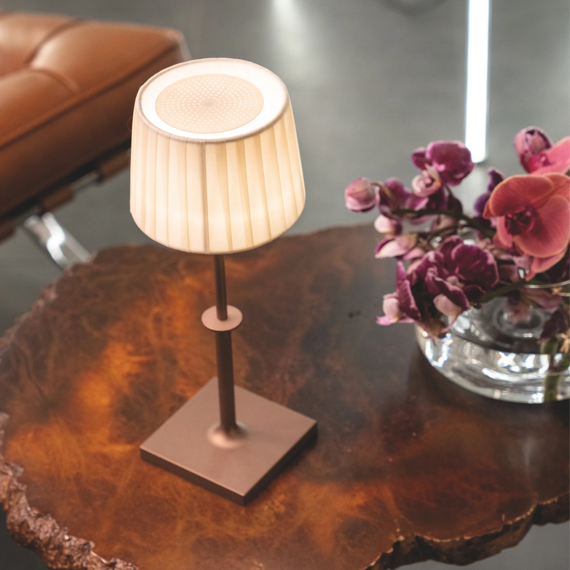 The bronze Poldina Classic Cordless Lamp from Zafferano on top of a wood coffee table in a business lounge.