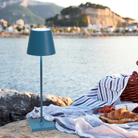 The avio blue Poldina Pro from Zafferano on an outdoor terrace with a picnic overlooking a lake.
