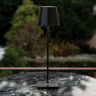 The black Poldina Pro from Zafferano in a garden on top of a black marble table.