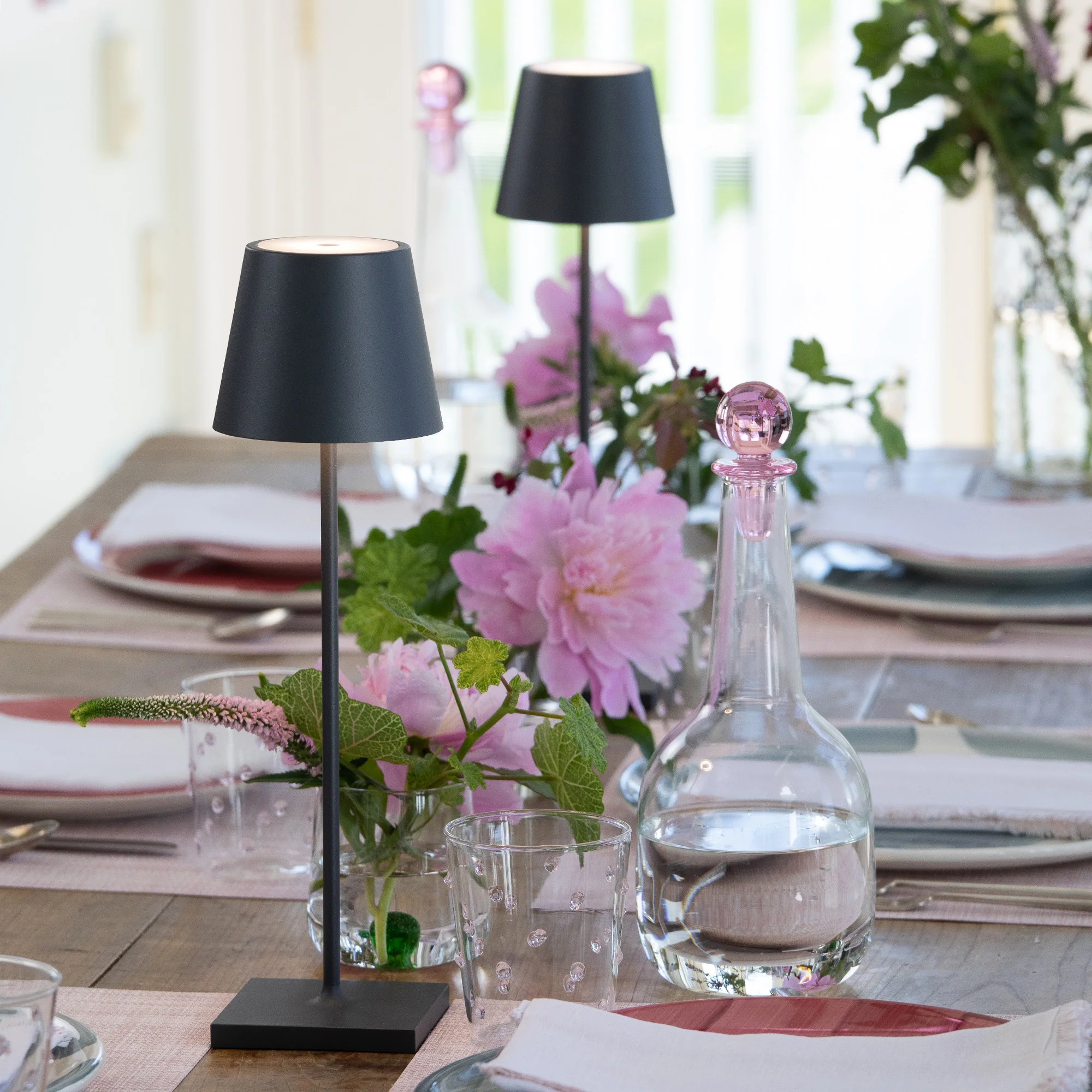 The dark gray Poldina Pro from Zafferano used on a dining table among various glasses, carafes and plates.