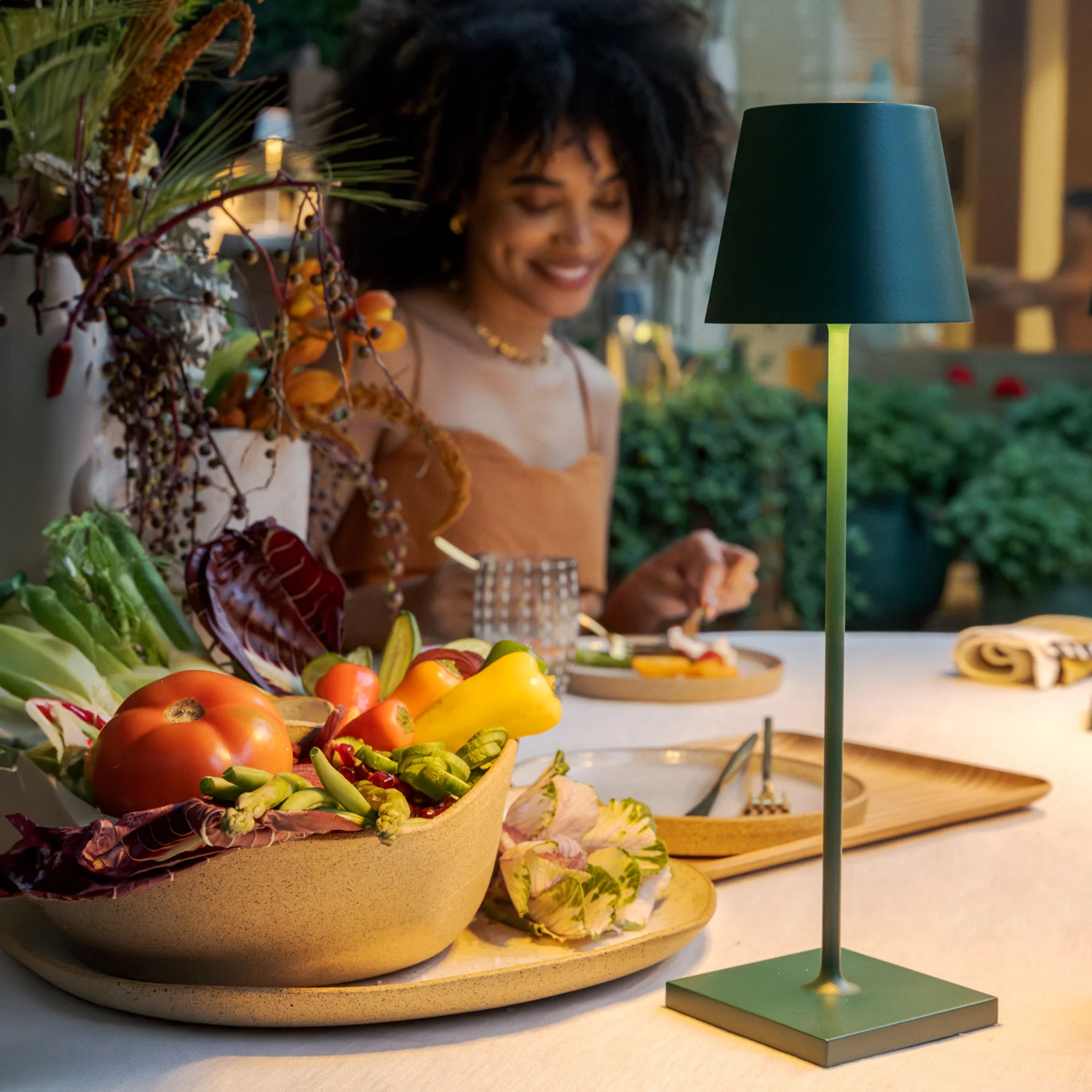 The dark green Poldina Pro from Zafferano on a dining table in an outdoor dining setting.
