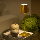 The gold leaf Poldina Pro from Zafferano in a living room beside a sofa on an end table.