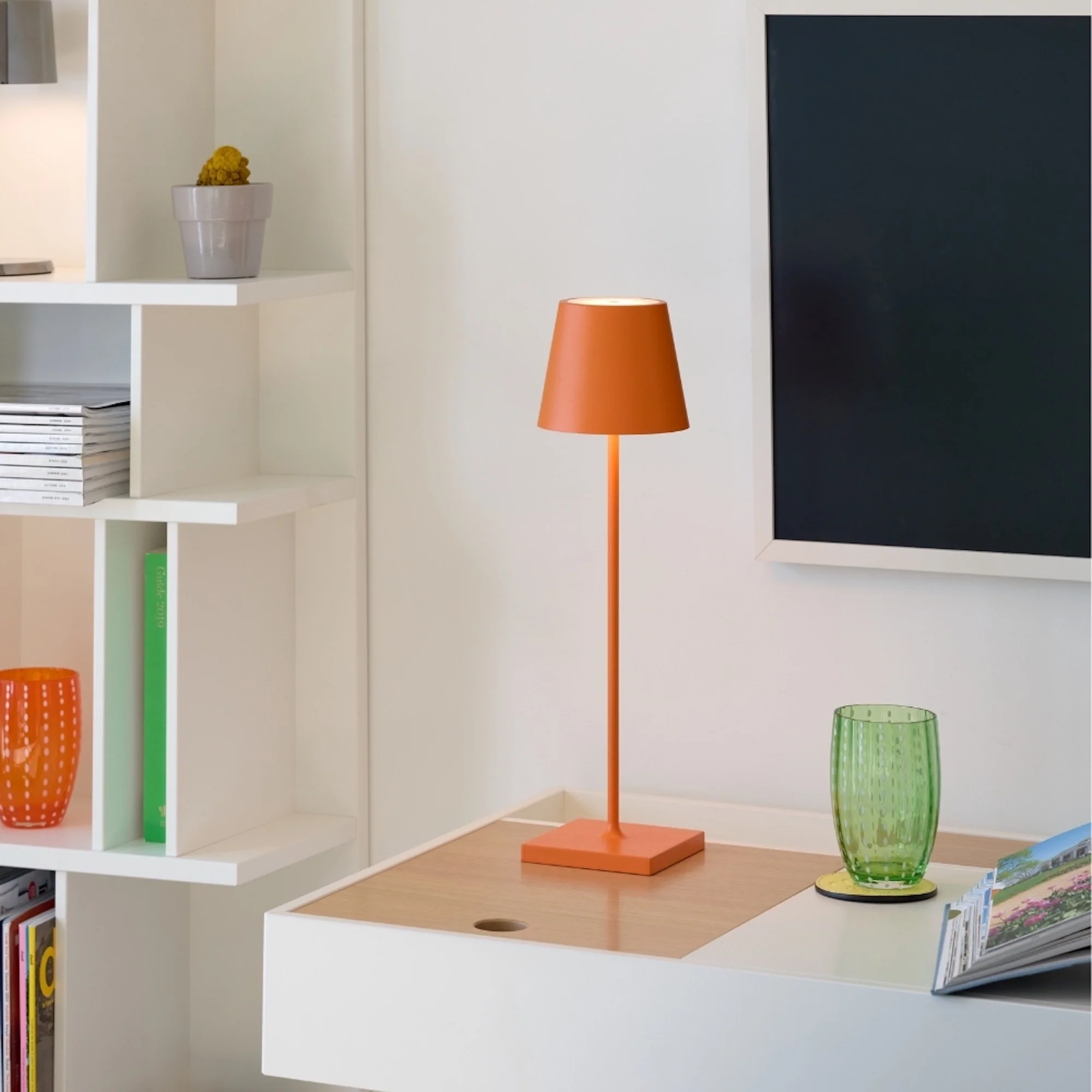 The orange Poldina Pro from Zafferano in a tv room on top of a console.