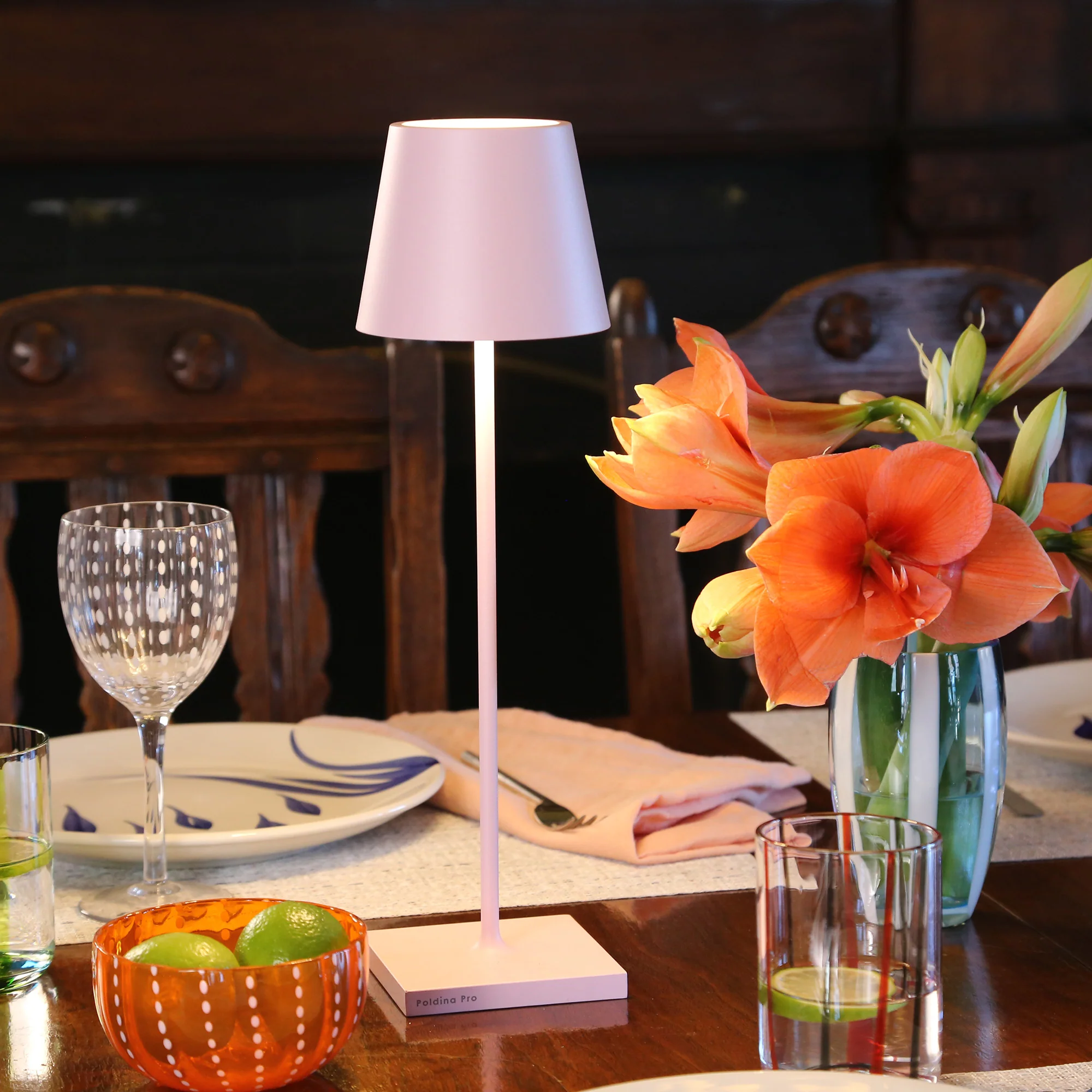 The pink Poldina Pro from Zafferano in a dining room on top of a wooden dining table with wooden dining chairs nearby.