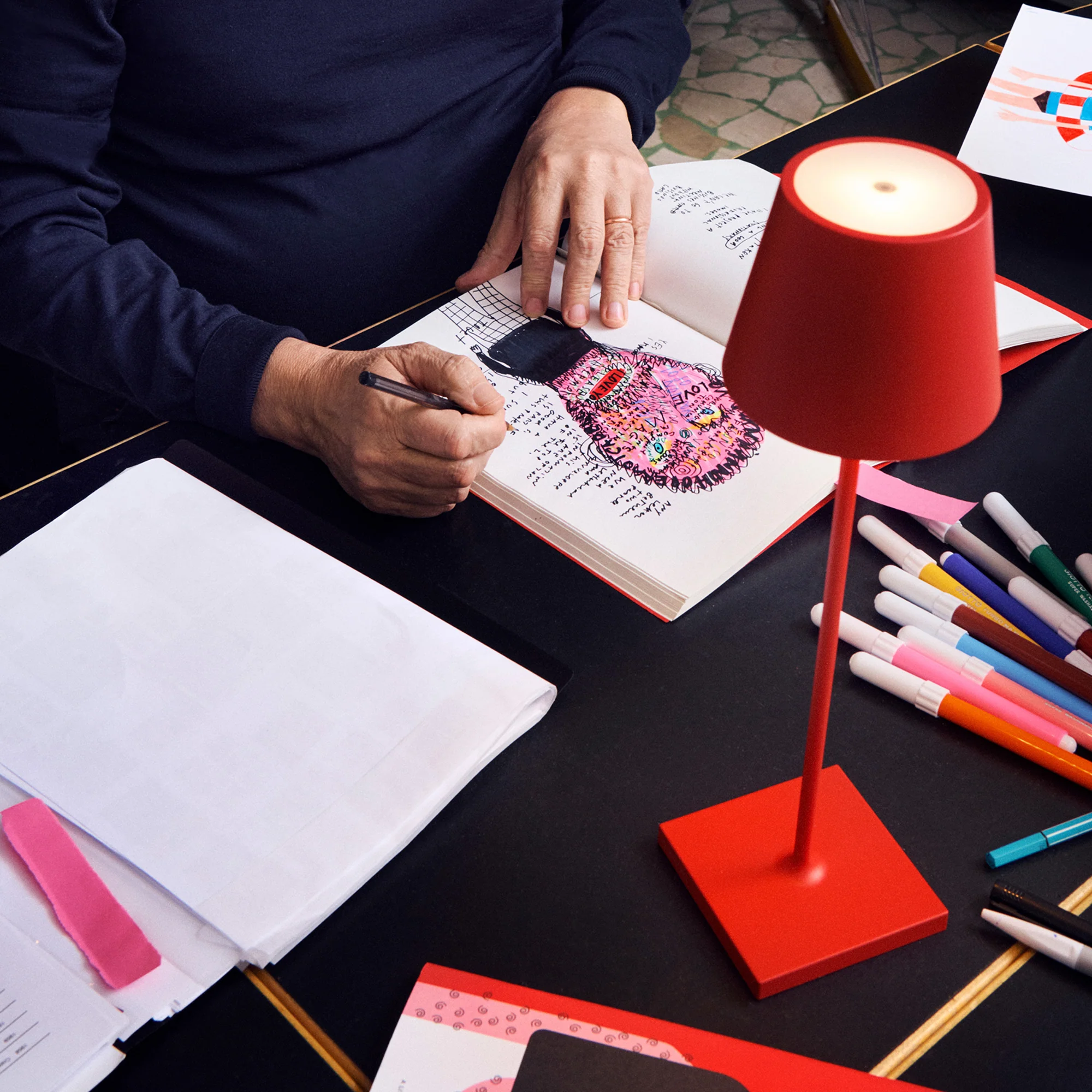 The red Poldina Pro from Zafferano in an art studio with an artist drawing.