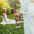 The rust Poldina Pro from Zafferano in a garden being carried by a woman towards a woman in a white dress.