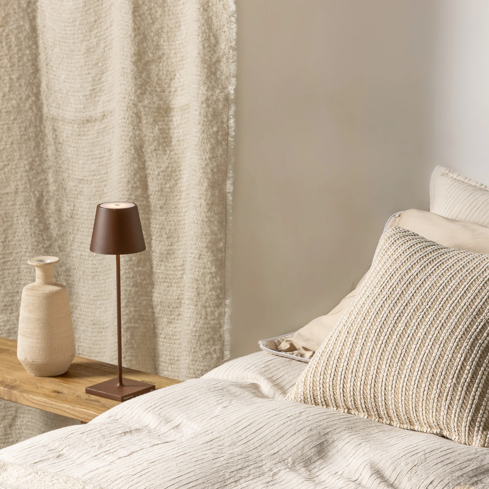 The rust Poldina Pro from Zafferano in a primary bedroom on a bench beside the bed.