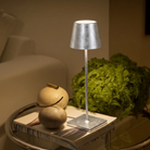 The silver leaf Poldina Pro from Zafferano in a luxury home on a glass end table next to a sofa.