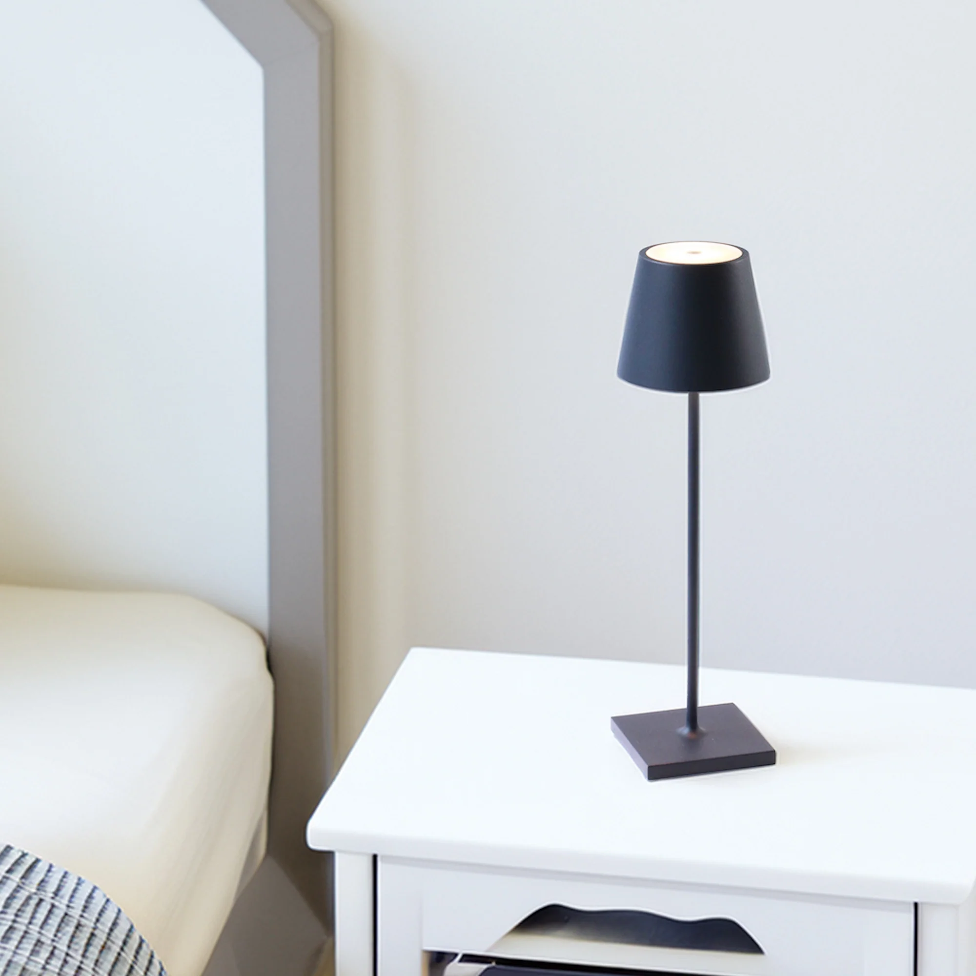 The steel blue Poldina Pro from Zafferano in a primary bedroom beside a bed.