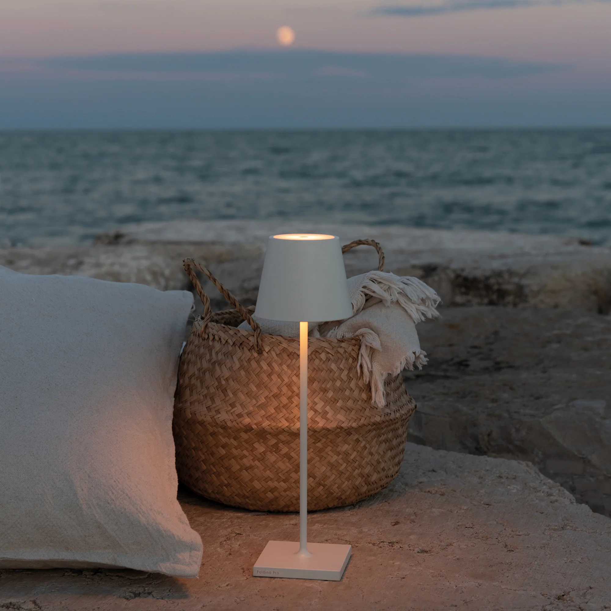 The white Poldina Pro from Zafferano in an outdoor living space overlooking an ocean.