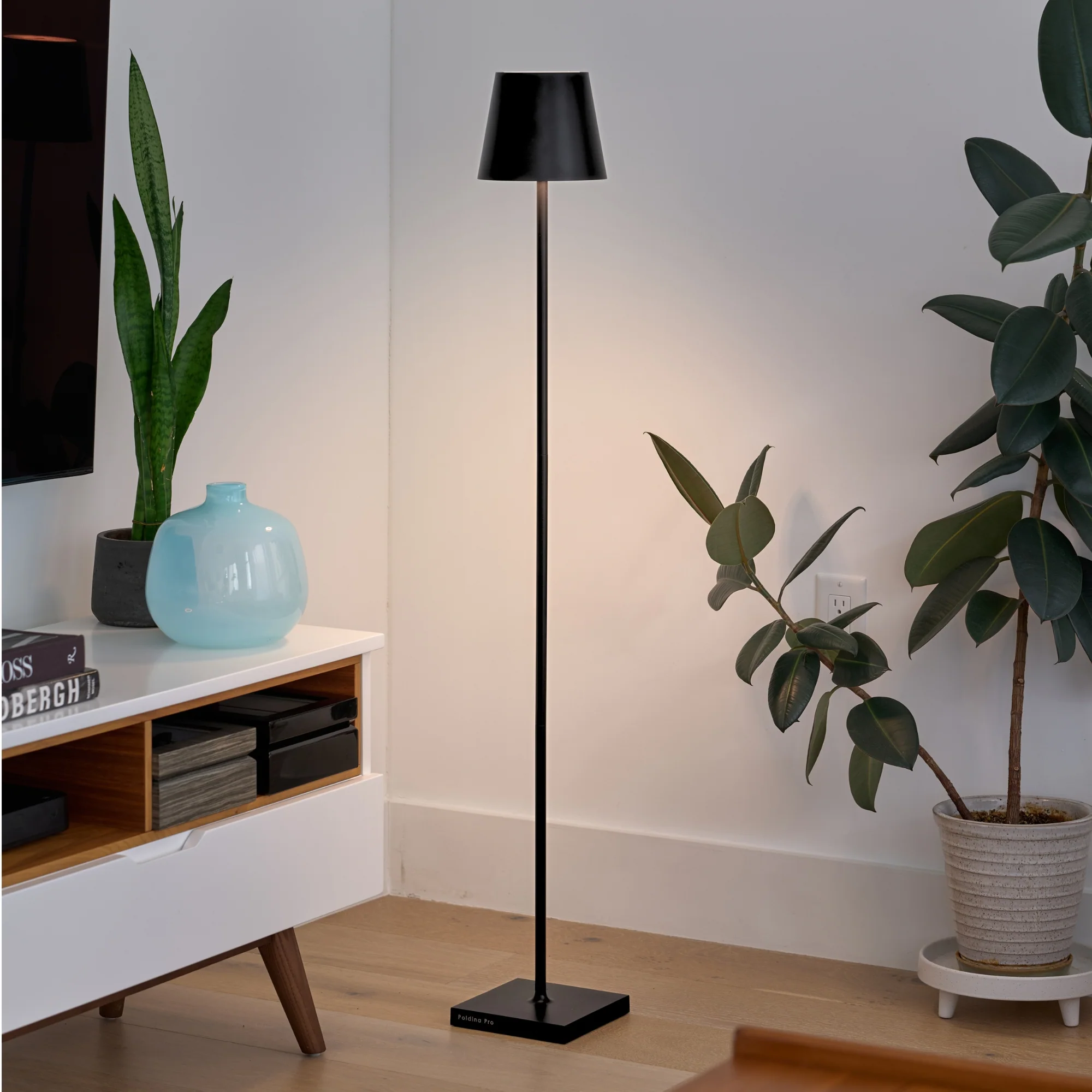 The black Poldina Pro L Floor Lamp from Zafferano in a TV room beside a console and television.