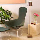 The rust Poldina Pro L Floor Lamp from Zafferano in a living room beside a lounge chair and ottoman.