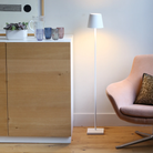 The white Poldina Pro L Floor Lamp from Zafferano in a dressing area next to a dresser and chair.