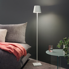 The white Poldina Pro L Floor Lamp from Zafferano in a guest bedroom beside a table and a bed.
