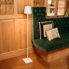 The white Poldina Pro L Floor Lamp from Zafferano in a lounge beside a padded bench.