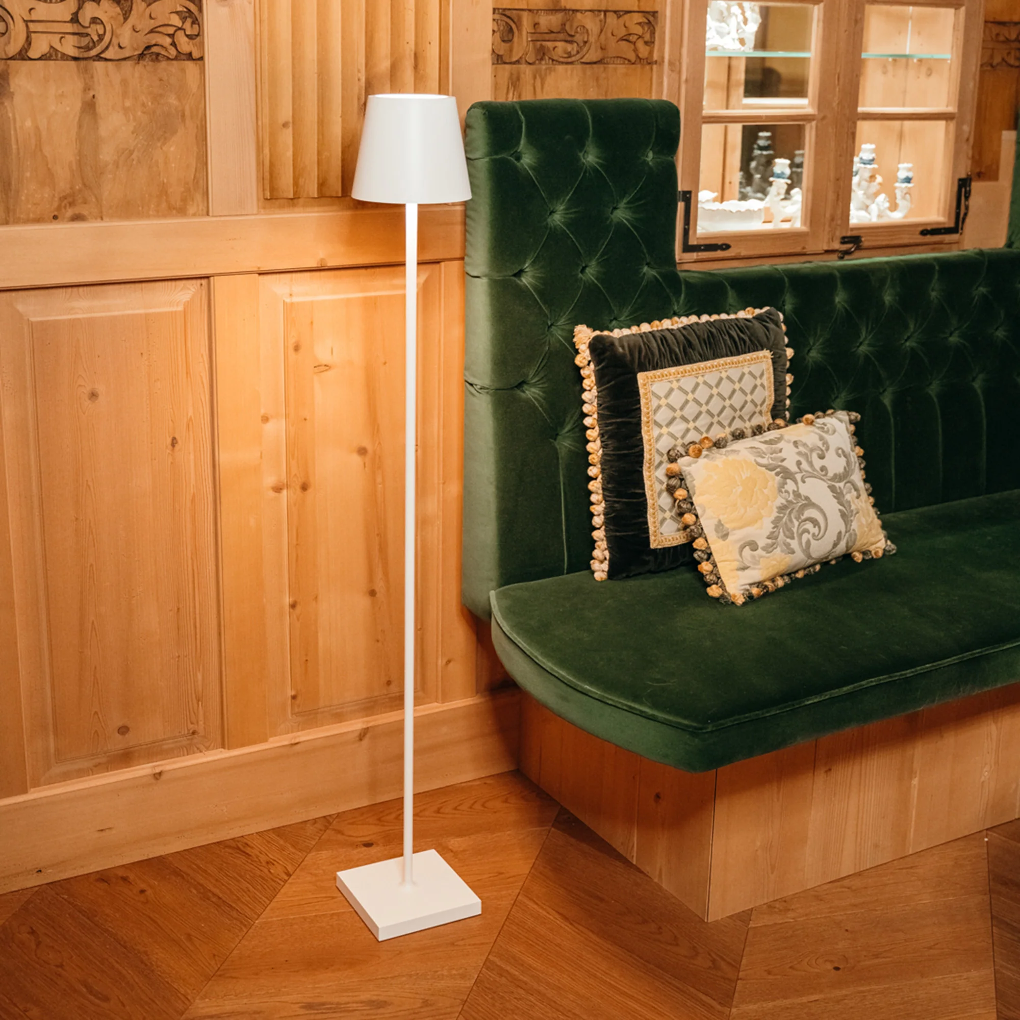 The white Poldina Pro L Floor Lamp from Zafferano in a lounge beside a padded bench.