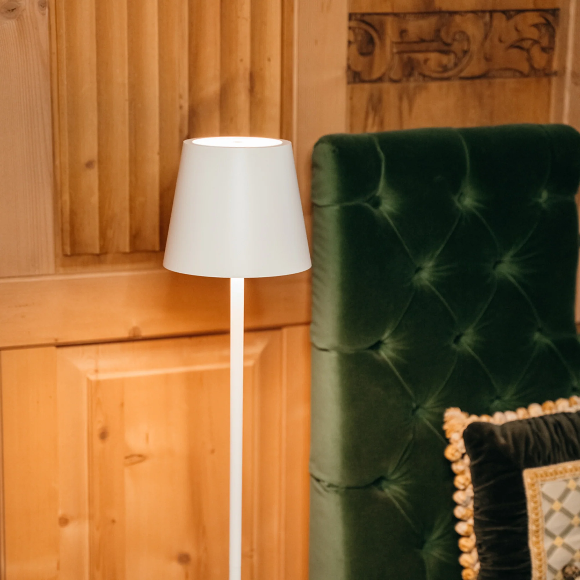 The white Poldina Pro L Floor Lamp from Zafferano in a reading space next to a seat.