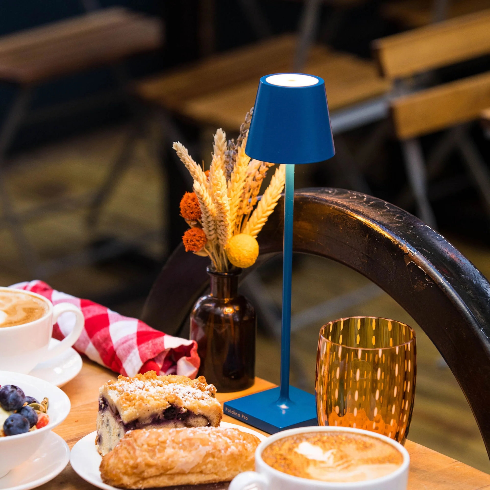 The capri blue Poldina Pro Micro Cordless Lamp from Zafferano on top of a table at a bakery.