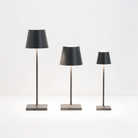 The dark gray Poldina Pro Micro Cordless Lamp from Zafferano alongside the other Poldina sizes.