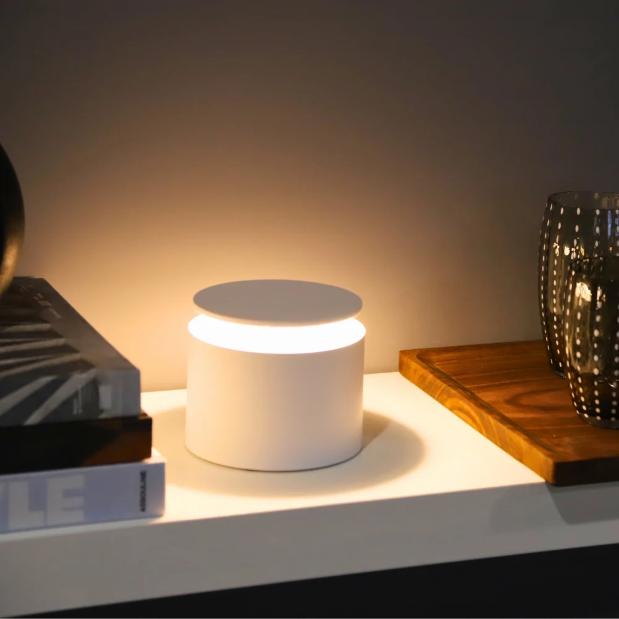 The white PushUp Pro Cordless Lamp from Zafferano in a bedroom on top of a table.