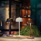 The matte black Theta Pro Cordless Lamp from Zafferano in a kitchen and dining area alongside the matte white and rust lights.