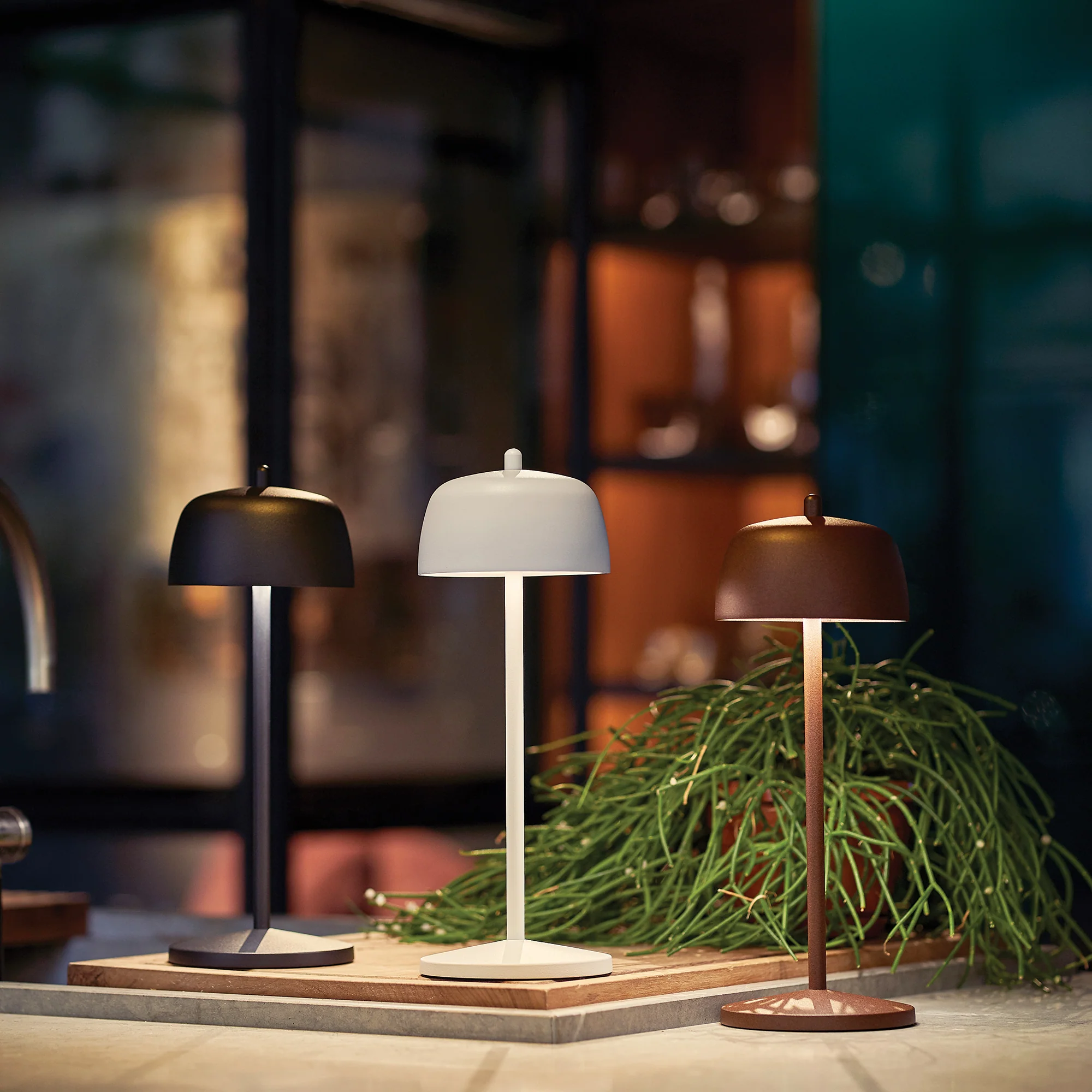 The matte black Theta Pro Cordless Lamp from Zafferano in a kitchen and dining area alongside the matte white and rust lights.