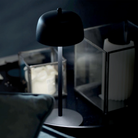 The matte black Theta Pro Cordless Lamp from Zafferano in a living room on an end table.