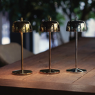 The polished chrome Theta Pro Cordless Lamp from Zafferano in a restaurant on a dining table alongside the polished gold and rose gold lamps.