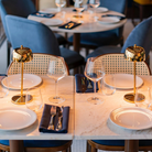 The polished gold Theta Pro Cordless Lamp from Zafferano on a marble dining table in a cafe.